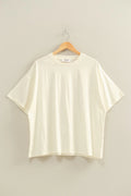Cream t-shirt on a wooden hanger against a beige background